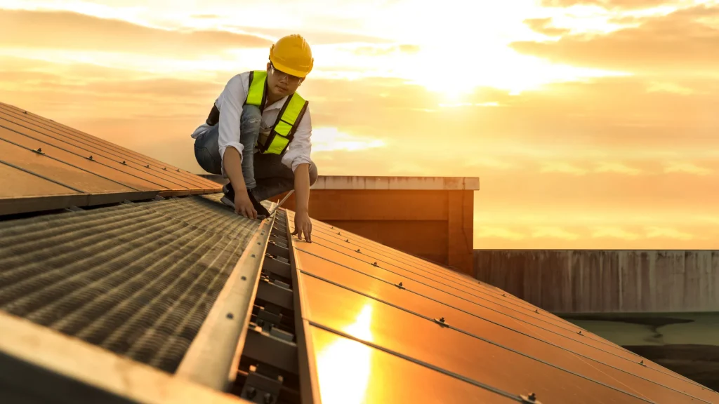 A worker adjusting solar panels during sunset, planning how many panels are needed to achieve 4.863 kW.