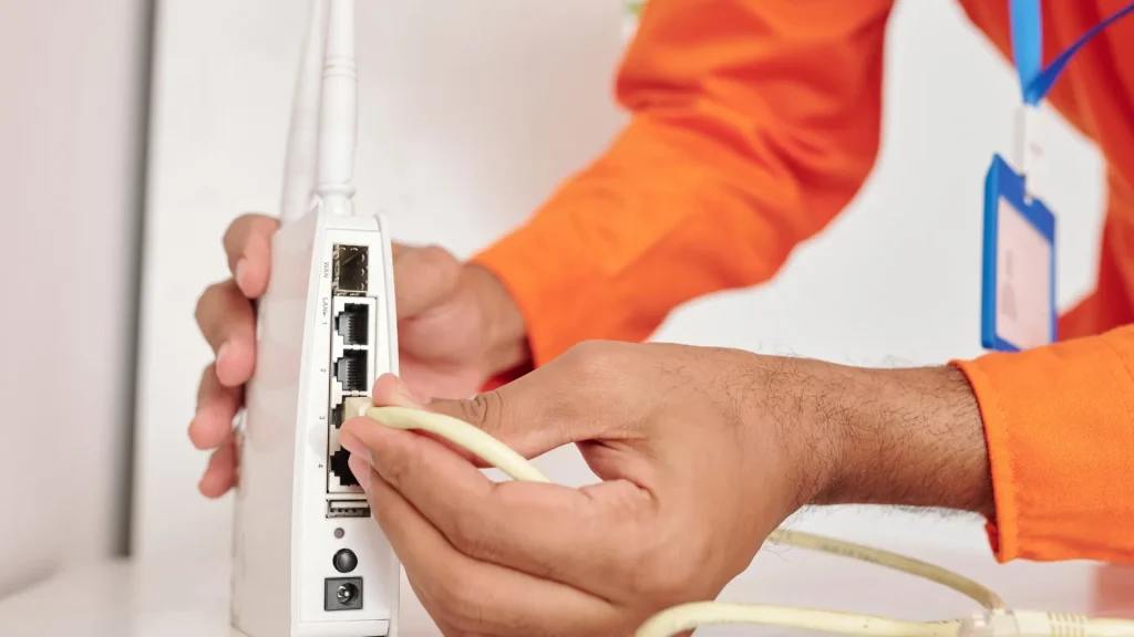 A person connecting an Ethernet cable to a wireless router, perfect for setting up a Point to Point Wireless Bridge Outdoor with Solar Panel support.
