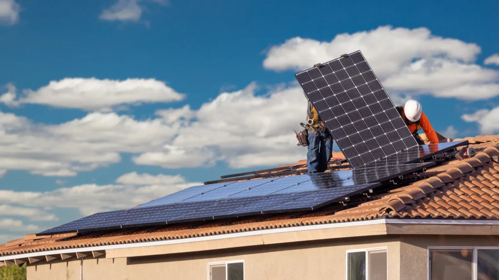 A worker installing a new solar panel on a rooftop, highlighting installation as a factor in damage.