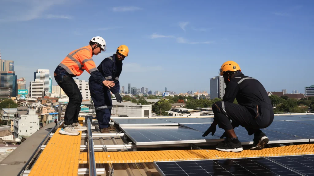  Technicians installing Trina Solar panels on a rooftop in an urban area, ensuring optimal energy generation and reduced costs.